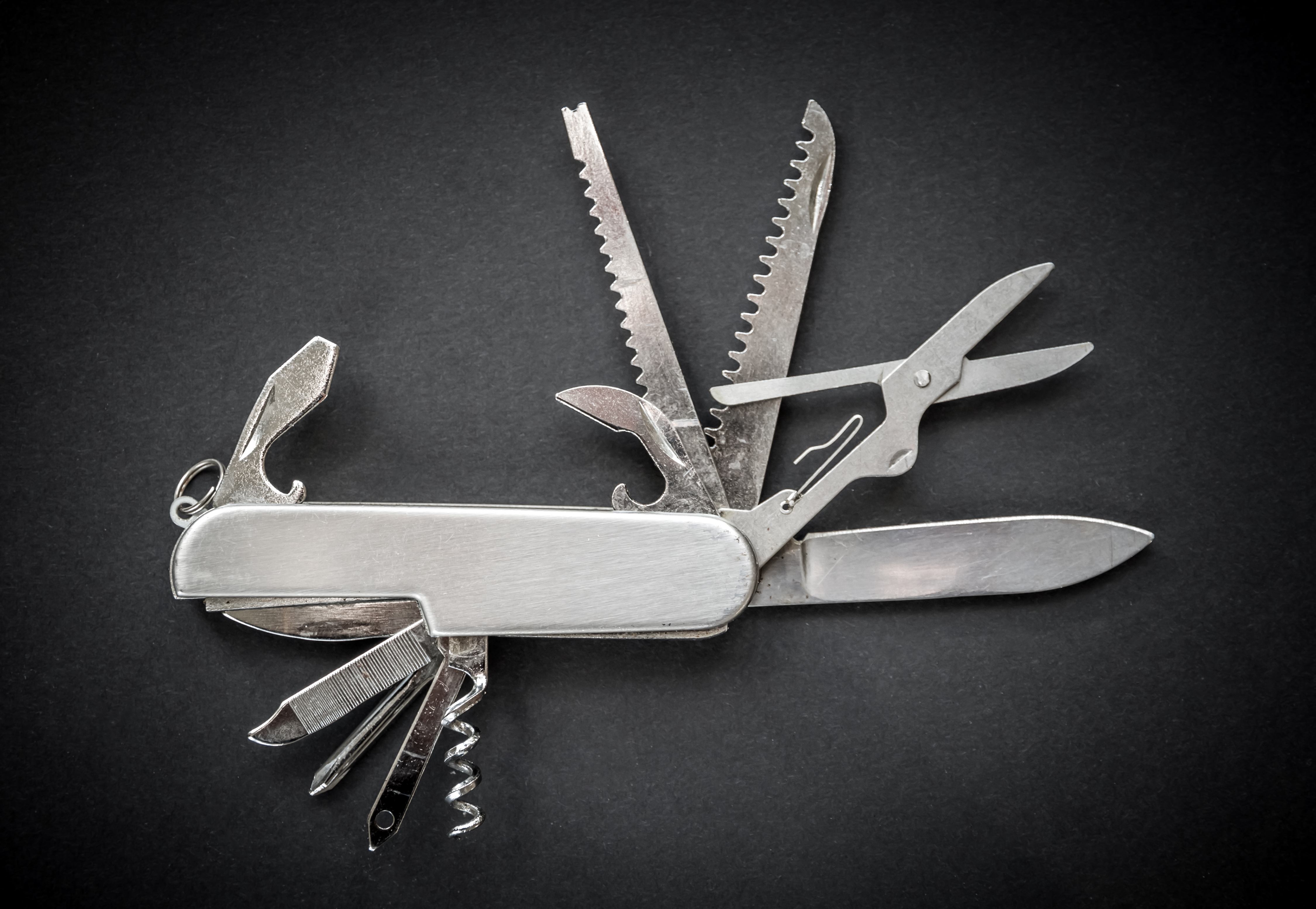 Open metallic pocket knife on a dark background